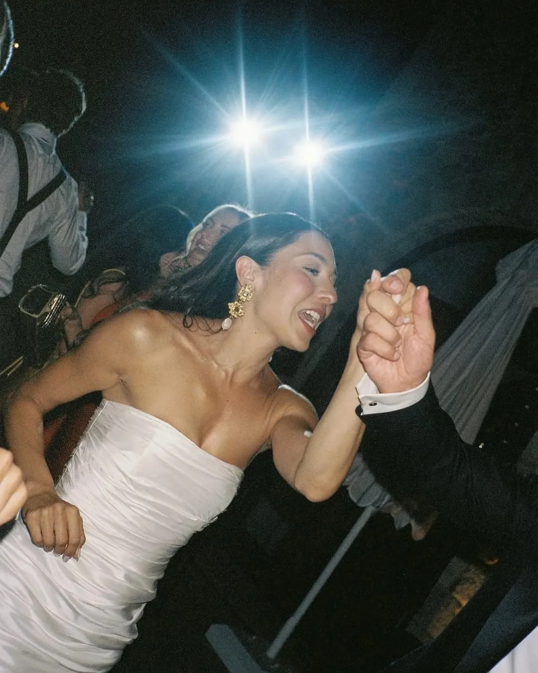 La novia bailando de la mano de su pareja bajo un flash azul