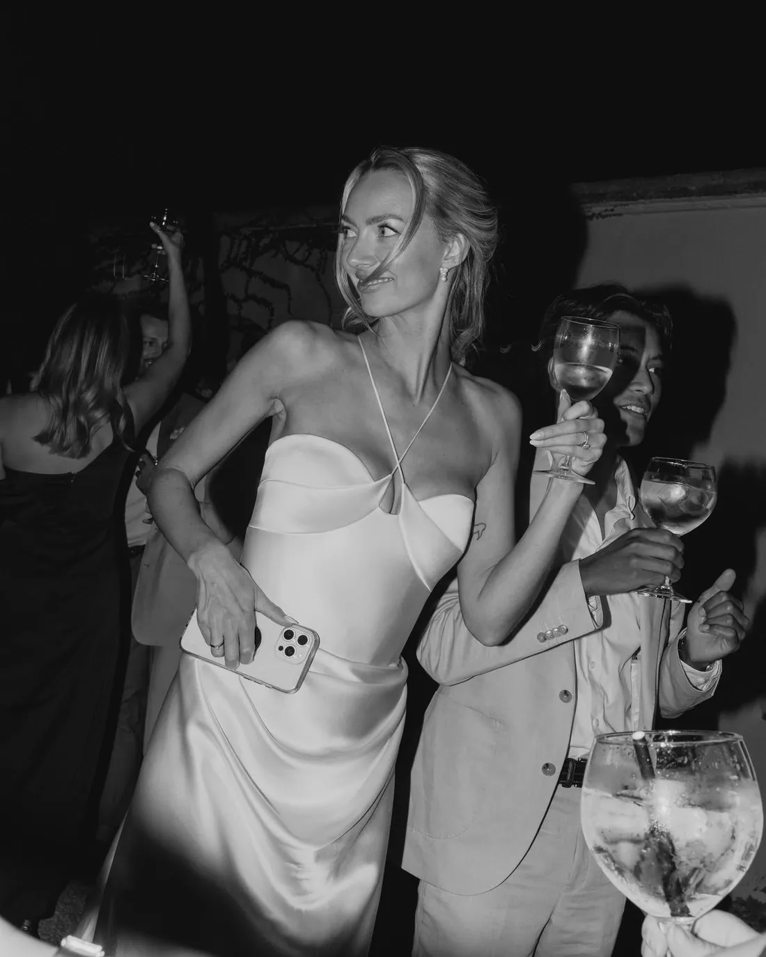 Una novia bailando con una copa en la mano durante la fiesta
